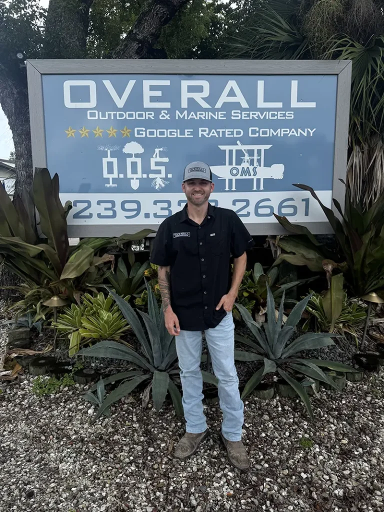 Photo of Clay Clawson, Marine Specialist for Overall Outdoor & Marine Services, standing in front of their business sign.