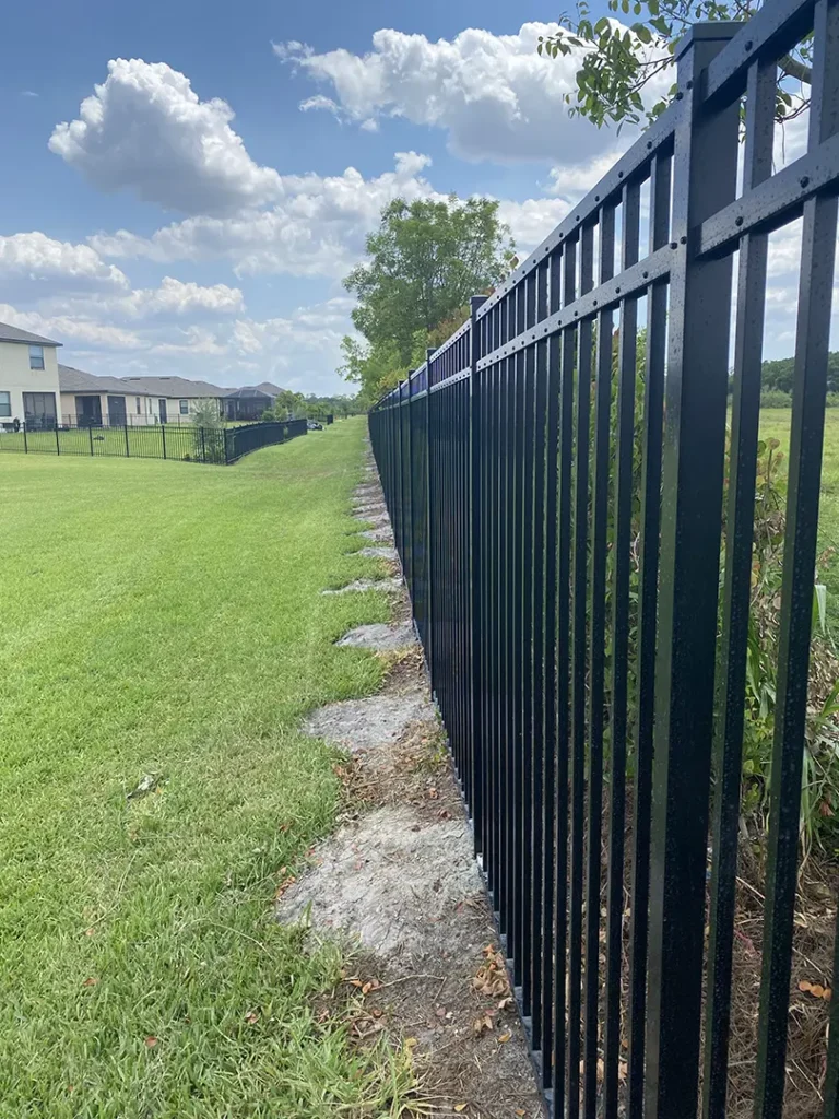A black metal fence installed alongside the edge of a private property in Naples, Florida.