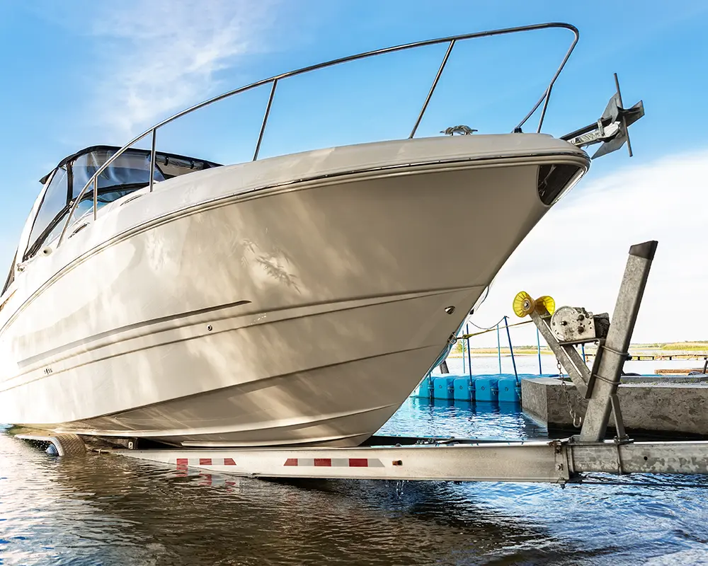 Spring Cleaning for Snowbirds: Preparing Your Dock for Southwest Florida's Summer Season. Featuring a luxury boat being pulled out of the water and onto a trailer.