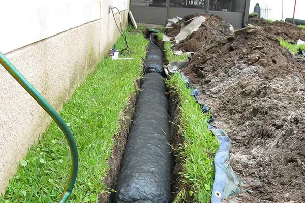 French drain being installed alongside a house by Overall Outdoor Services.